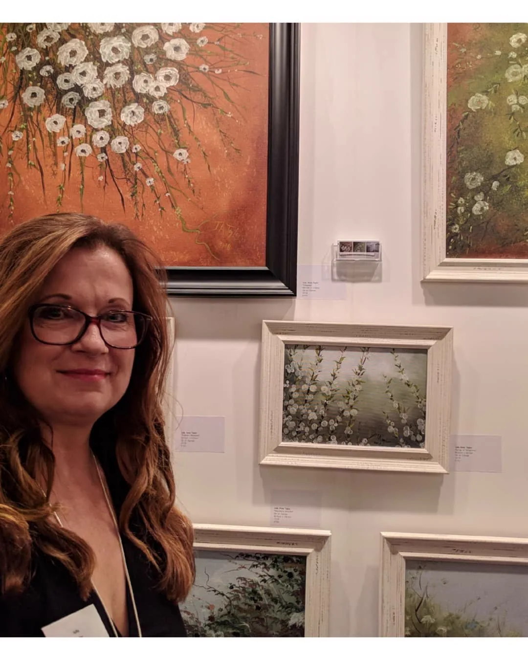 Julia Anne Taylor at the Parallax Art Fair, Kensington Town Hall, with her paintings behind her